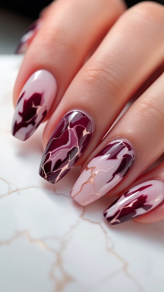 A close-up of nails featuring a marble effect design with wine undertones, pink, white, and gold accents.