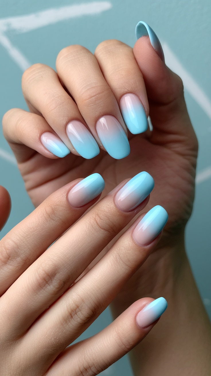 Close-up of soft ombre powder blue nails showcasing a gentle gradient from deep to light blue.