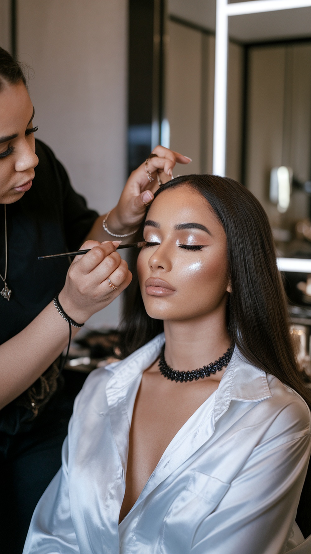 A makeup artist applying shimmering eyeshadow on a woman's eyelids, showcasing a radiant makeup look.